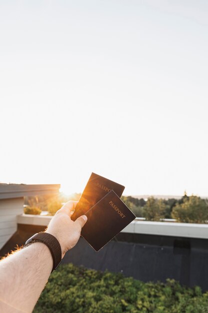 Pessoa que mostra os passaportes no pôr do sol