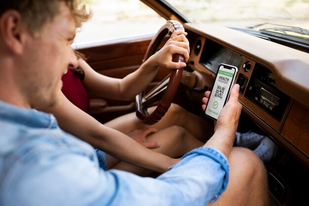 Foto grátis pessoa segurando passaporte virtual de saúde em smartphone no carro