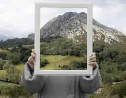 Foto grátis pessoa segurando quadro com conceito de paisagem de natureza aberta