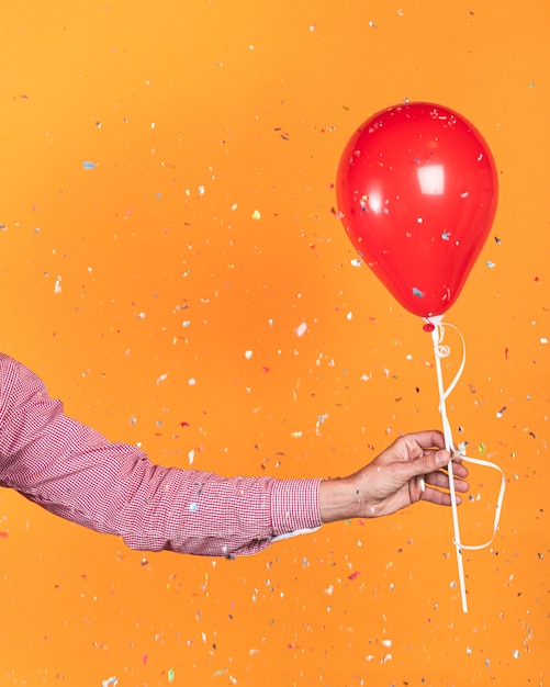 Foto grátis pessoa, segurando um balão vermelho e confetes