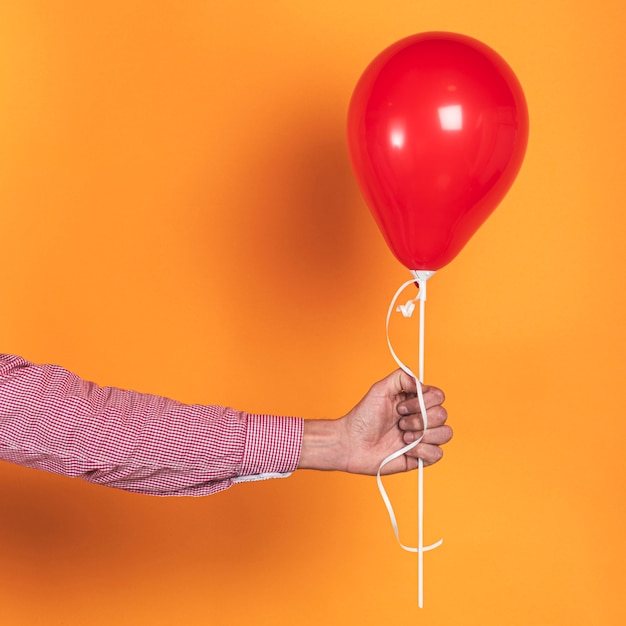 Pessoa, segurando um balão vermelho em fundo laranja