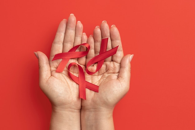 Pessoa segurando um símbolo de fita do Dia Mundial da Aids