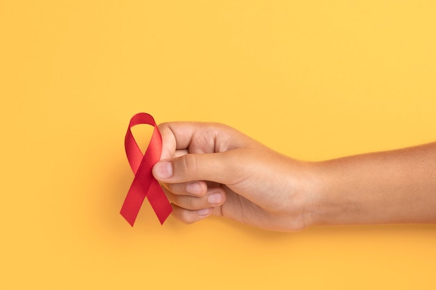 Foto grátis pessoa segurando um símbolo de fita do dia mundial da aids