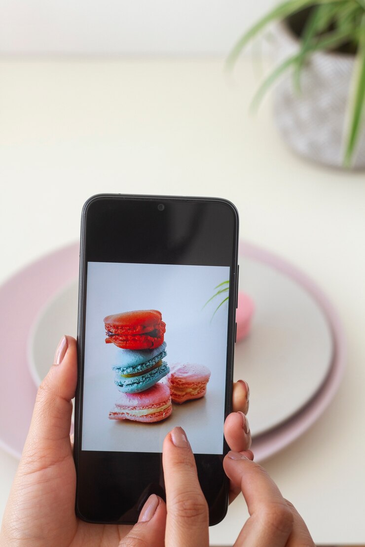 Foto grátis pessoa tirando foto de macarons em forma de coração em placas com smartphone