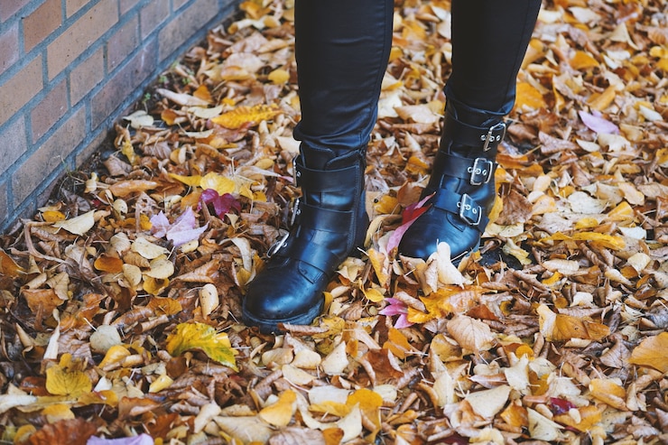 Foto grátis pessoa usando botas de couro preto andando nas folhas coloridas