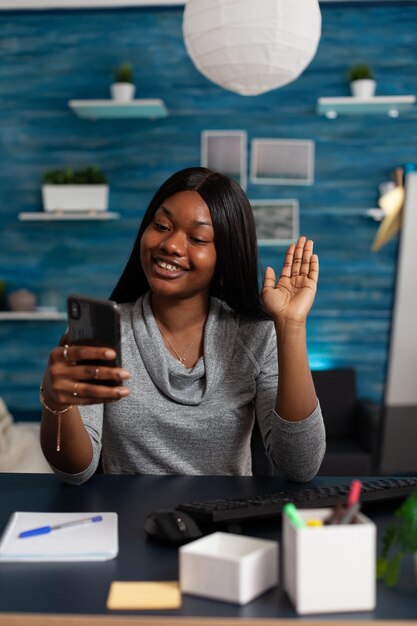 Pessoa usando videochamada no telefone para falar com colegas de casa. Empreendedor fazendo reunião de negócios em smartphone com videoconferência online, acenando para a câmera do telefone móvel. Trabalho remoto