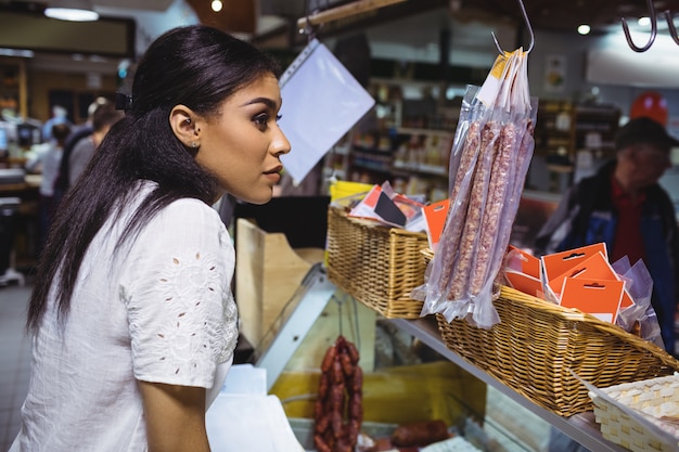 Pessoal feminino pensativo em pé no balcão de carne