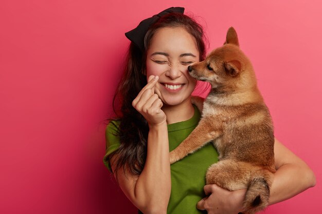 Pessoas, amam o conceito de animais. Menina coreana positiva brinca com cachorro shiba inu, fazendo mini gesto de coração