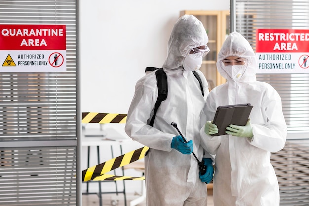 Pessoas com equipamento de proteção desinfetando uma área perigosa