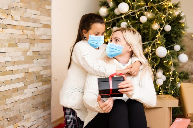 Pessoas com presentes usando máscaras faciais durante surto de coronavírus e gripe no Natal. Proteção contra vírus e doenças, quarentena doméstica. COVID-2019.