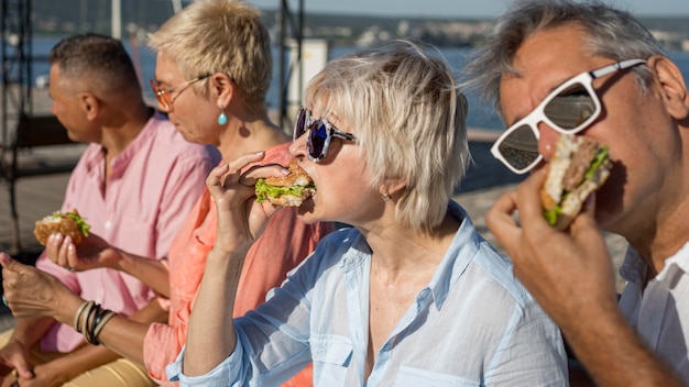 Pessoas comendo hambúrgueres juntas ao ar livre