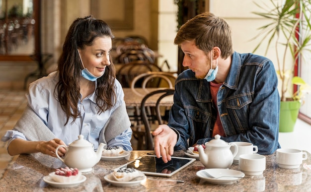 Pessoas conversando no restaurante com máscaras médicas no queixo