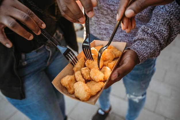 Pessoas de alto ângulo comendo nuggets em embalagens de comida para viagem