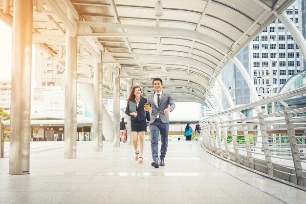 Pessoas de negócios caminhando pelo escritório da passagem. Sorrindo um para o outro.