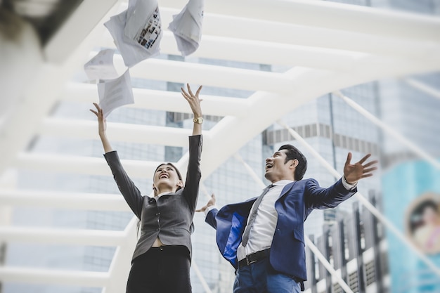 Pessoas de negócios estão vomitando papéis, enquanto estão em frente ao prédio de escritórios. Conceito de sucesso empresarial.