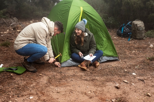 Pessoas de tiro completo com mapa e tenda