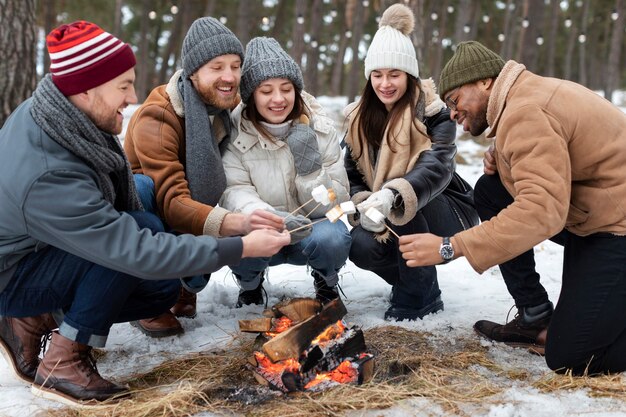 Pessoas de tiro completo com marshmallows perto do fogo