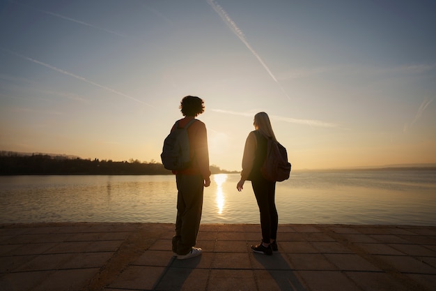 Foto grátis pessoas de tiro completo posando ao pôr do sol