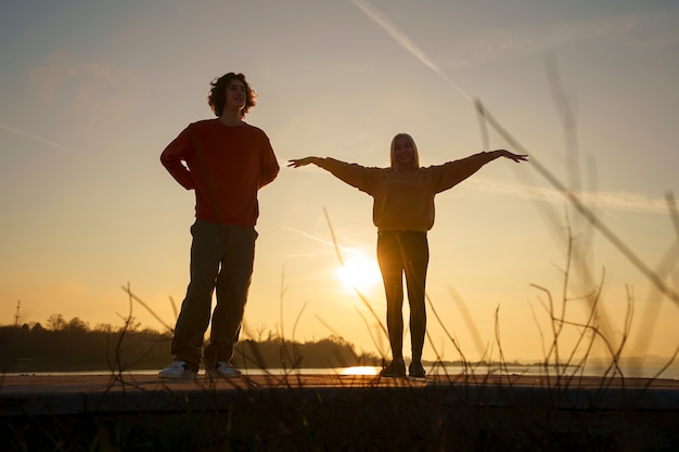 Pessoas de tiro completo posando ao pôr do sol