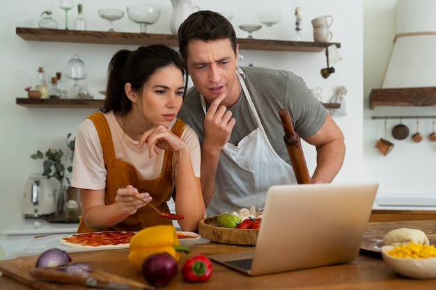 Pessoas de tiro médio cozinhando pizza juntas