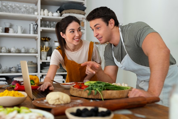 Pessoas de tiro médio cozinhando pizza juntas