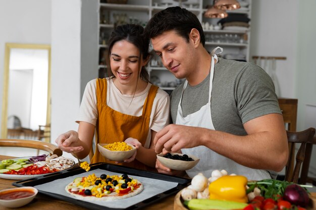 Pessoas de tiro médio cozinhando pizza juntas