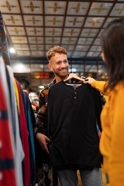 Pessoas de vista lateral olhando roupas em brechó