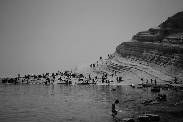 Pessoas desfrutando de um dia na praia perto de uma colina rochosa