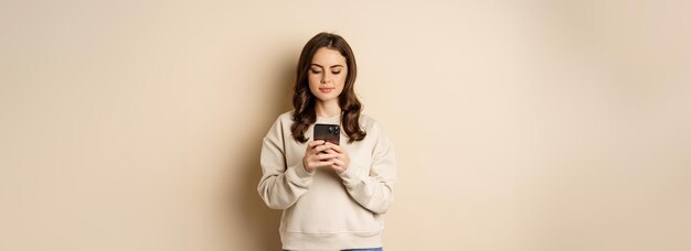 Pessoas e tecnologia celular linda mulher estilosa usando aplicativo de smartphone para celular sorrindo e