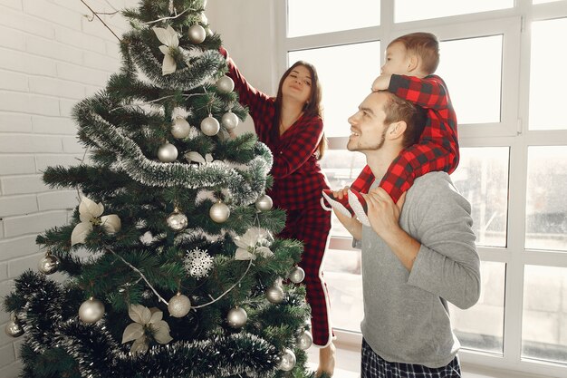 Pessoas em casa. Família de pijama. Mãe com marido e filho em uma decoração de Natal.