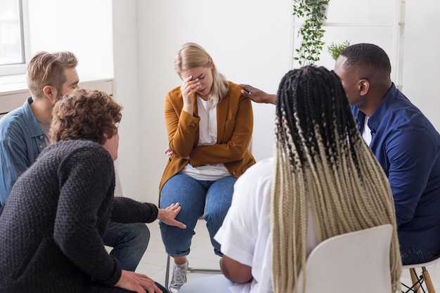 Pessoas em tiro médio ajudando mulher triste