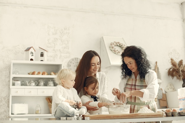 Foto grátis pessoas em uma cozinha. família prepara bolo. mulher adulta com filha e netos.