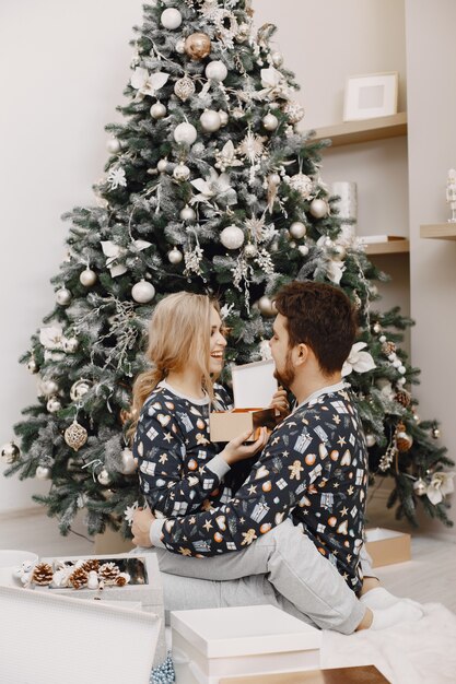 Pessoas em uma decoração Christman. Homem e mulher com pijama idêntico. Família em casa.