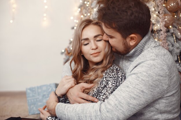 Pessoas em uma decoração de Natal. Homem com um suéter cinza. Família em casa.