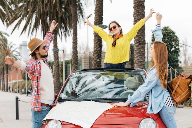 Pessoas felizes em pé perto de carro com roteiro