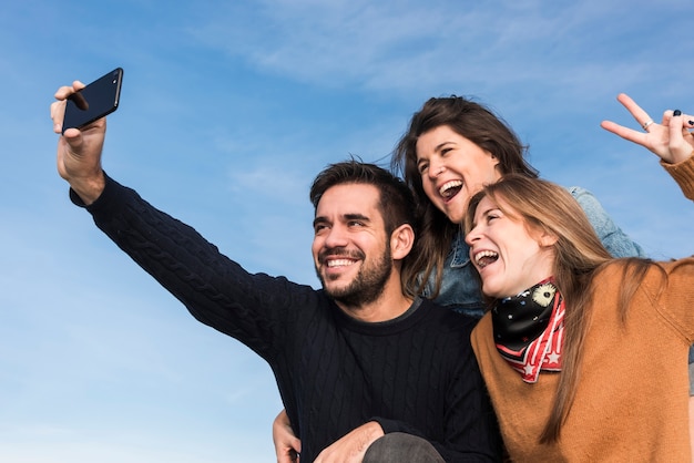 Pessoas felizes tomando selfie no fundo do céu azul