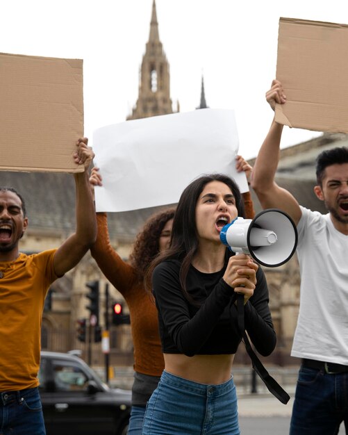 Pessoas gritando em protesto com megafone de perto