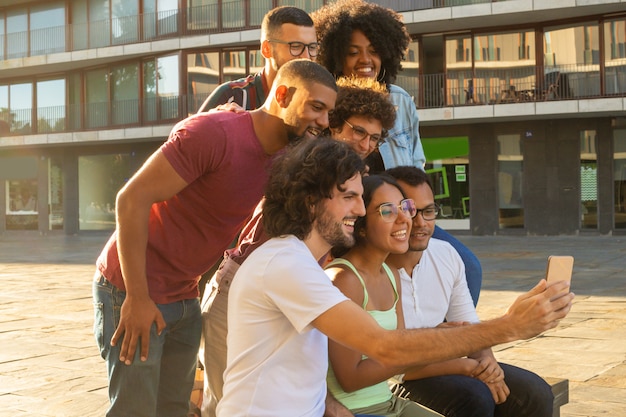 Foto grátis pessoas inter-raciais alegres felizes tomando selfie de grupo