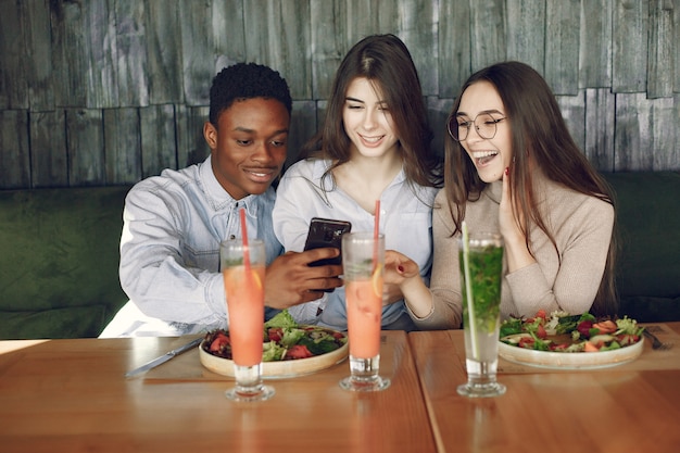 Pessoas internacionais sentados à mesa com saladas e cocktails