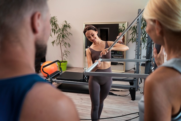 Foto grátis pessoas na aula de reformador de pilates exercitando seus corpos