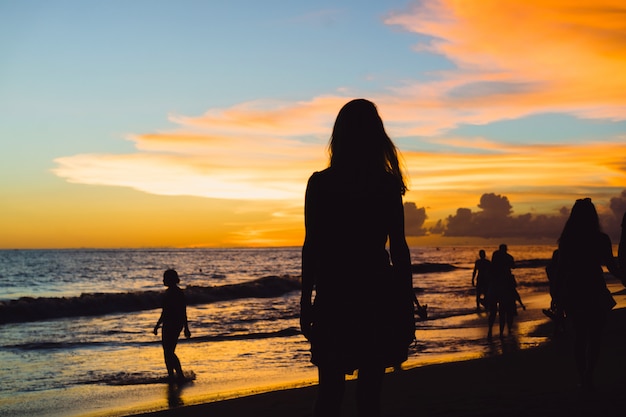 Foto grátis pessoas na praia ao pôr do sol.