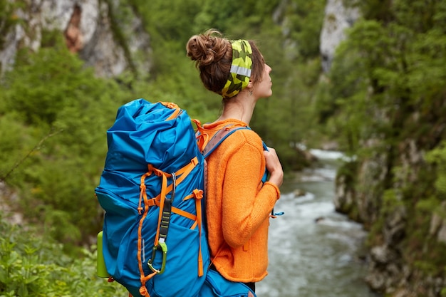 Pessoas, recreação e conceito de viagem. Foto lateral de uma mulher pensativa carregando uma mochila, em uma expedição de verão