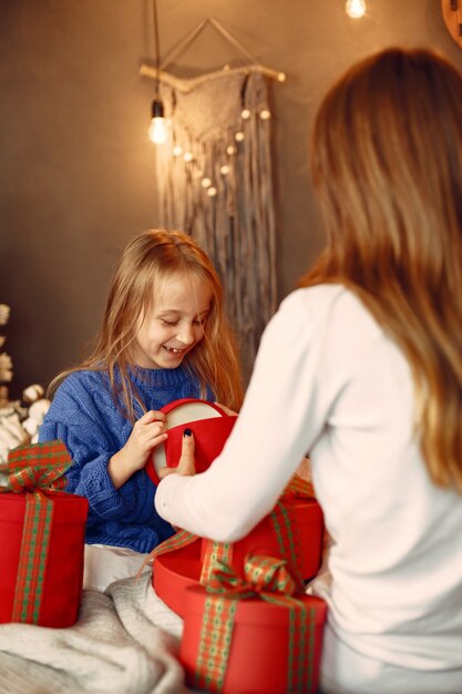 Pessoas reparando pelo Natal. Mãe brincando com sua filha. Família está descansando em uma sala festiva. Criança com um suéter azul.