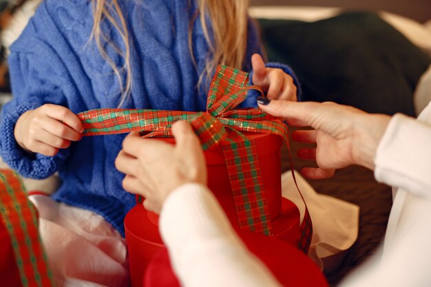 Pessoas reparando pelo Natal. Mãe brincando com sua filha. Família está descansando em uma sala festiva. Criança com um suéter azul.