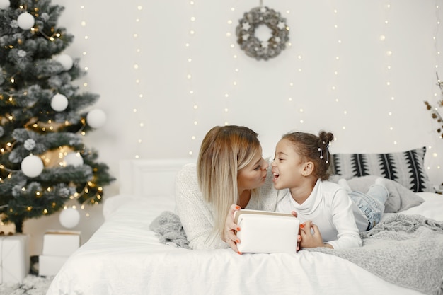 Pessoas reparando pelo Natal. Mãe brincando com sua filha. Família está descansando em uma sala festiva. Criança com um suéter.