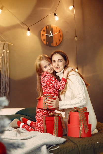 Pessoas reparando pelo Natal. Mãe brincando com sua filha. Família está descansando em uma sala festiva.