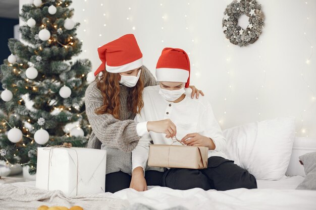 Pessoas reparando pelo Natal. Tema Coronavirus. Mãe brincando com seu filho. Rapaz com uma camisola branca.