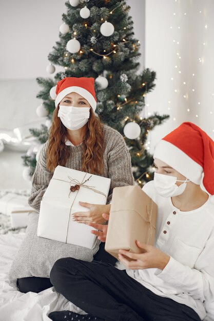 Pessoas reparando pelo Natal. Tema Coronavirus. Mãe brincando com seu filho. Rapaz com uma camisola branca.