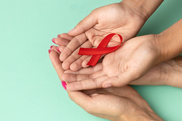 Pessoas segurando um símbolo vermelho do dia mundial da aids