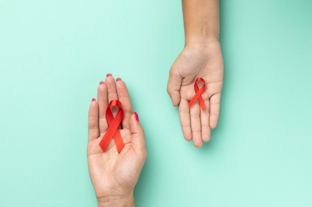 Pessoas segurando um símbolo vermelho do Dia Mundial da Aids